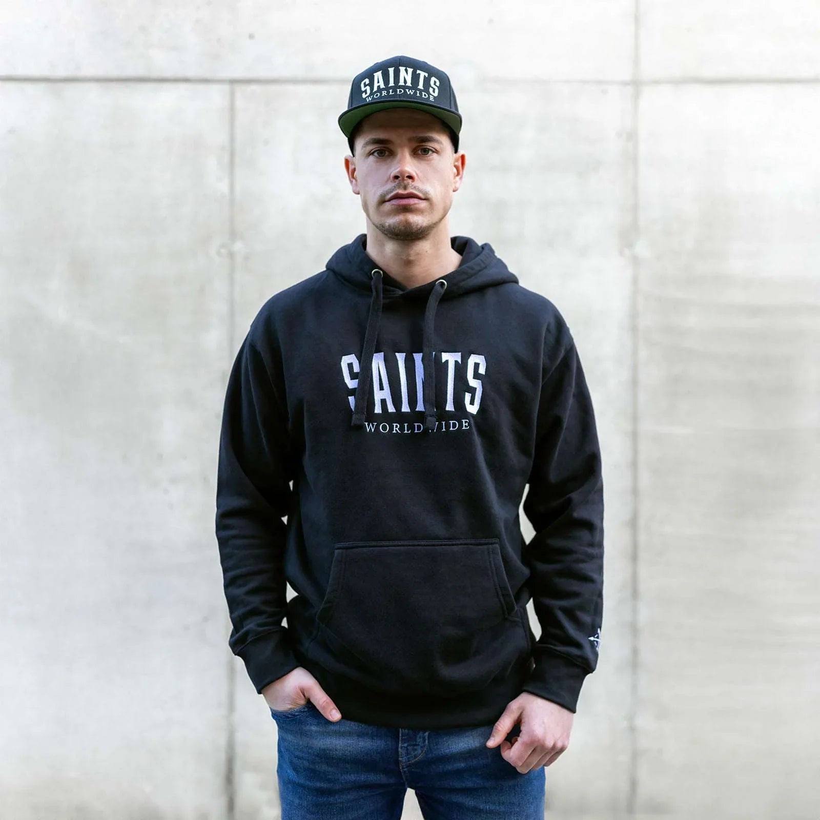 Male model wearing Christian black hoodie with Saints Worldwide logo on front