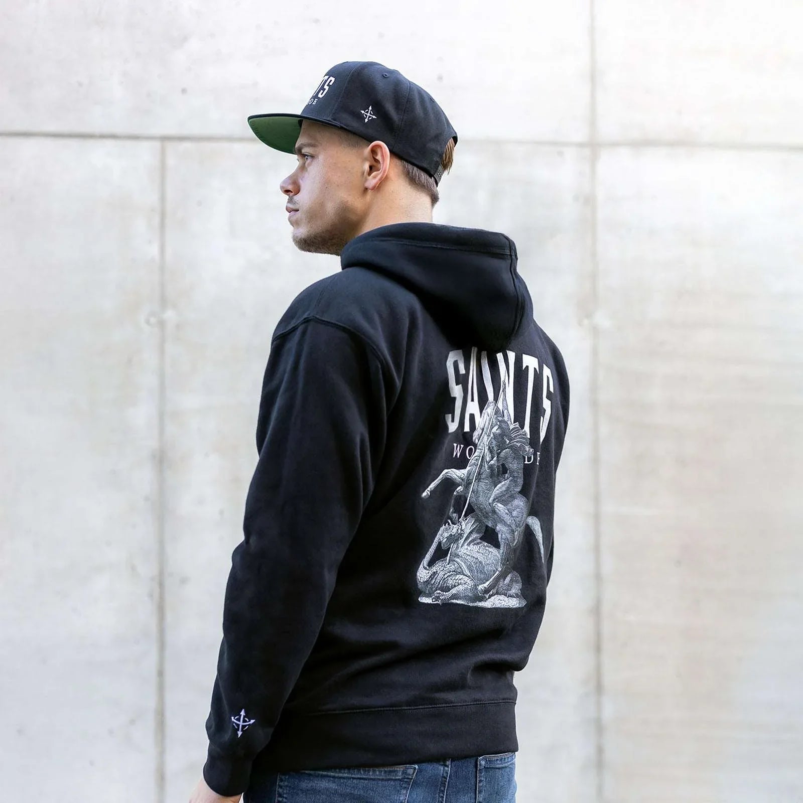 Male model wearing black Saints Worldwide Christian hoodie with back embroidery
