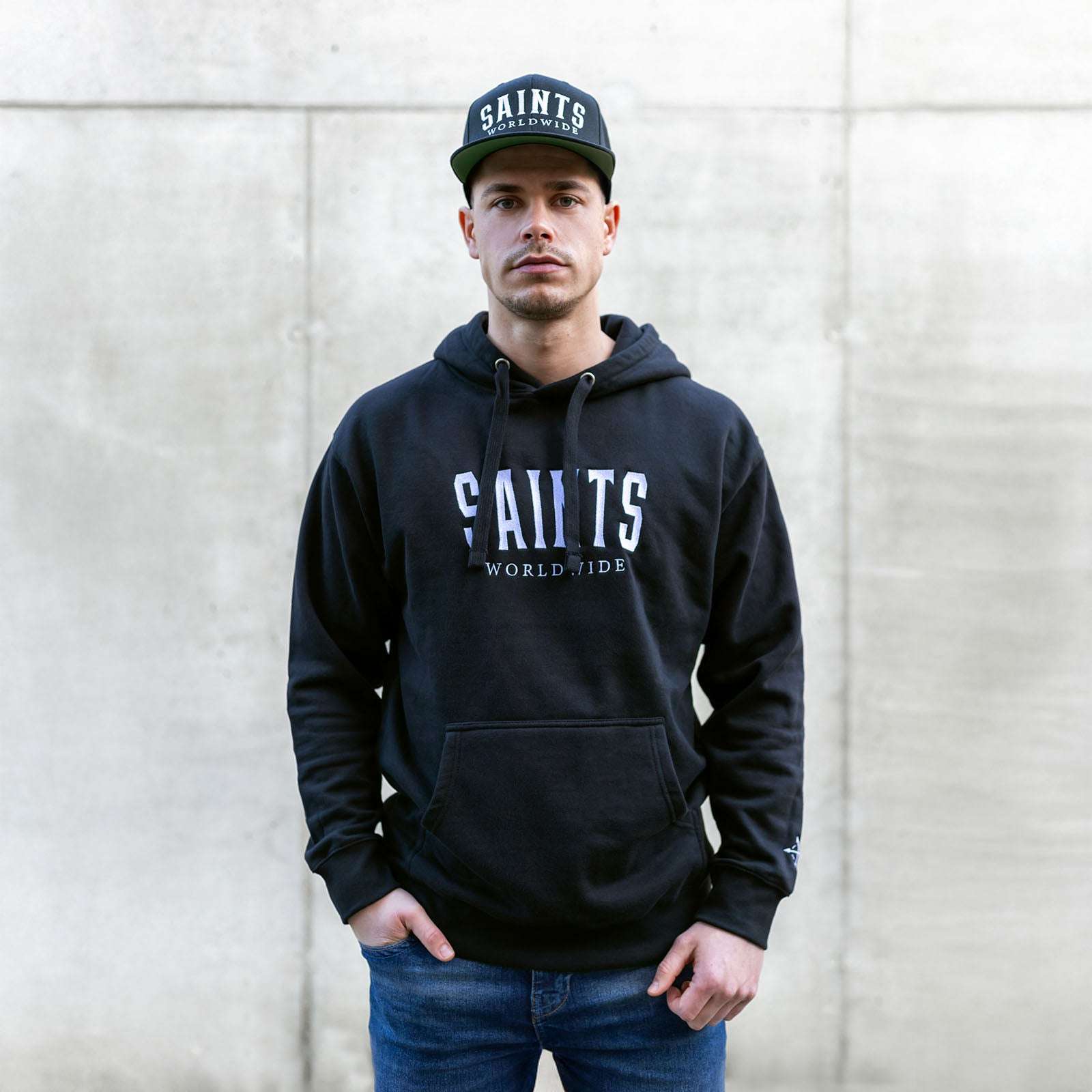 Male model wearing Christian black hoodie with Saints Worldwide logo on front