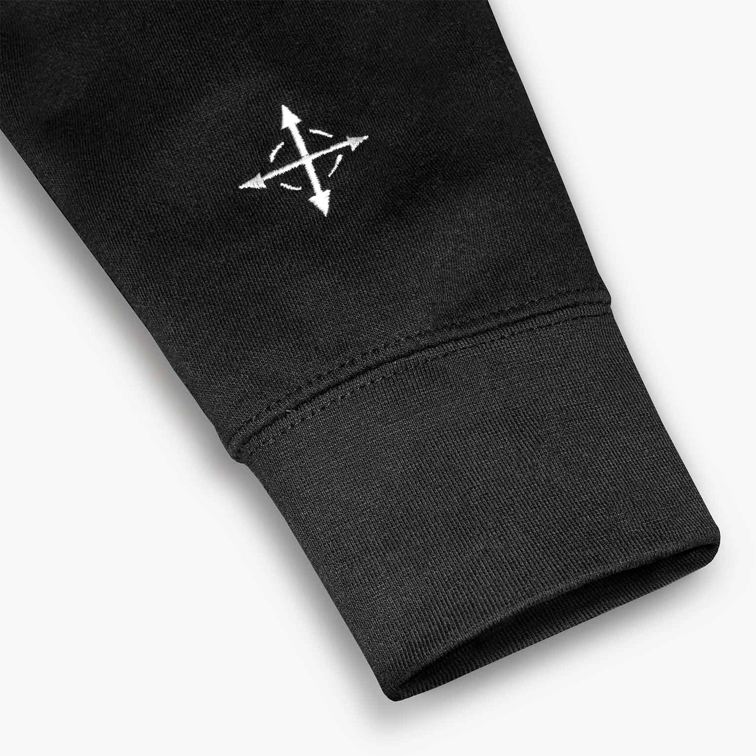Close-up of compass arrow embroidery on hoodie sleeve – Christian symbolism